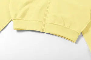 Vue détaillée d'un sweat à capuche zippé jaune pâle avec un ourlet côtelé à la taille