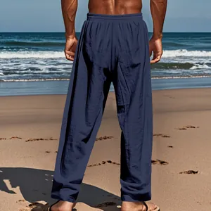 Back view of comfortable navy blue loose linen trousers for men on a sunny beach background