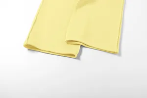 Gros plan de l'ourlet du pantalon de jogging jaune, montrant les coutures et le tissu.