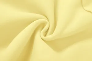 Gros plan d'un tissu en maille jaune pâle doux montrant une texture et des plis