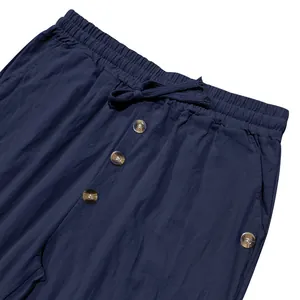 Close-up of navy blue drawstring linen pants with decorative tortoiseshell buttons.