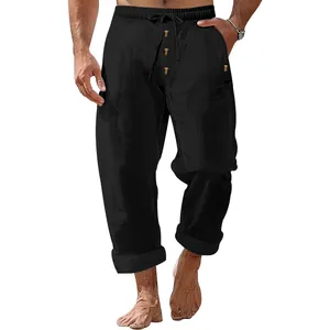 Close-up of men's loose black linen pants with drawstring and button detailing.