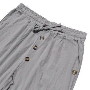 Detailed view of grey linen-style pants featuring elastic drawstring waist and decorative buttons.