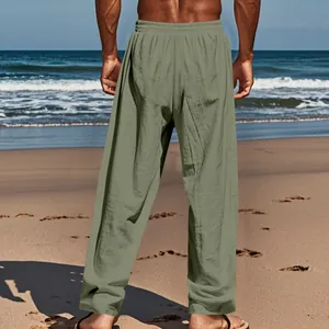 Back view of men's loose fit sage green linen casual pants against a beach background