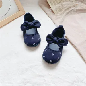 Close-up of navy blue toddler canvas shoes featuring large bows and embroidery details