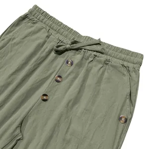 Detailed view of men's sage green linen pants with drawstring waist and decorative buttons
