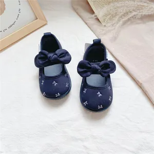 Close-up of navy blue baby girls' canvas shoes with large bows and floral embroidery