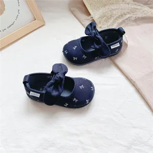 Detail view of navy blue girls canvas shoes with large bows and floral patterns