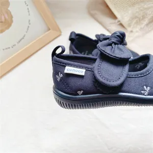 Detail of navy blue girls canvas shoes featuring a cute bow and brand label