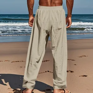 Rear view of men's loose beige linen straight-leg casual trousers on a sunny beach