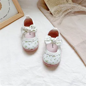 Close-up view of white floral canvas baby girl shoes with cute bowknot decorations