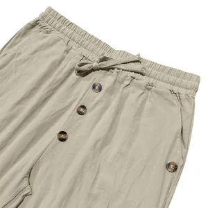 Detail of men's linen pants featuring drawstring waist and decorative buttons.