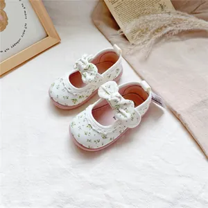 Close-up detail of baby girl floral canvas shoes featuring cute bow knots and soft pink soles