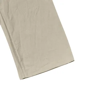 Detailed close-up view of linen fabric texture and hem stitching on khaki men's straight pants