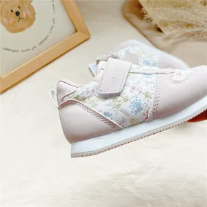 Detailaufnahme des rosa Blumenmusters und der Steppnähte an diesem Mädchen-Sneaker