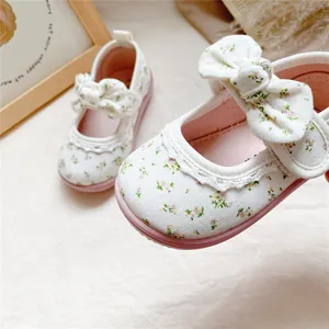 Detailed view of baby girl floral canvas shoes with a large bow and soft pink sole