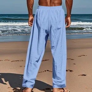 Detailed back view of men's casual light blue linen straight-leg pants on beach sand