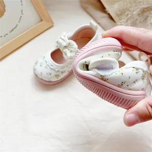 Flexible floral canvas baby girl shoes with bow accent showing soft rubber sole