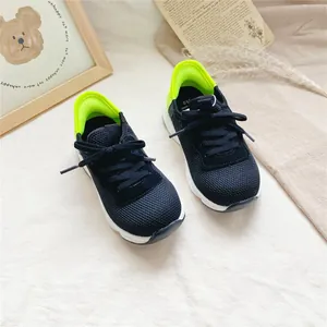 Detailed view of breathable black children's sneakers with vibrant neon green heels