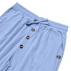 Close-up of men's blue linen pants showing drawstring waist and decorative buttons.