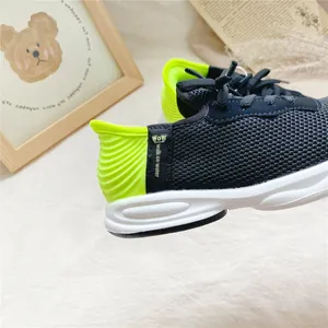 Close-up of black mesh kids sneakers with neon green heel and walk on water tag.