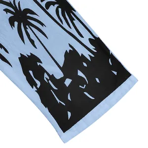 Close-up detail of light blue linen fabric featuring a black tropical palm tree print