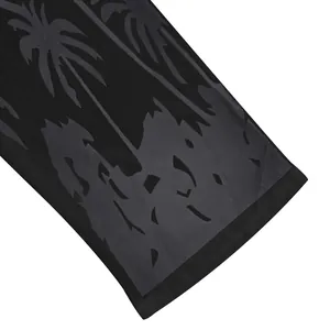 Close-up macro detail of black palm tree print on men's summer linen beachwear fabric
