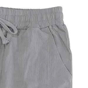 Detailed macro shot of the elastic waistband and drawstring on gray linen trousers.