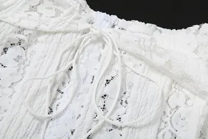 Vista ravvicinata della delicata trama in pizzo bianco e dei dettagli con lacci di un abito elegante