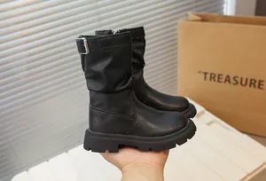 Détail de bottes mi-mollet noires pour filles avec semelles compensées et boucles métal