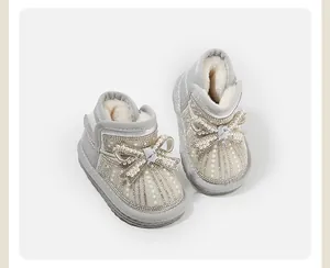 Close-up of silver baby girl snow boots with elegant pearl bow and rhinestone details.