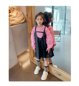 Niña con zapatillas de cuero blanco a la moda con calcetines de rayas y sudadera