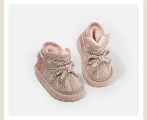Detailed view of pink baby snow boots with pearls and a decorative bow