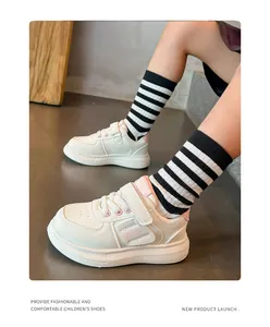 Primer plano de zapatillas blancas para niños con detalles rosas y cierre de velcro.