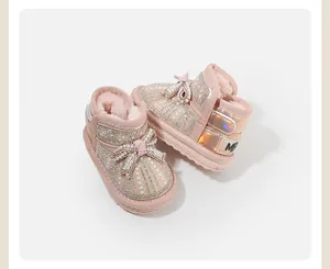 Close-up view of pink glittery baby snow boots with pearl bow and warm fur lining