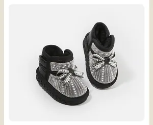 Close-up of baby girl's snow boots with pearl and rhinestone bow details.