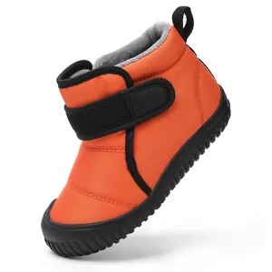 Close-up of orange children's winter snow boot with warm fleece lining and Velcro strap