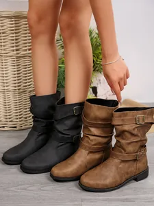 Close-up detail of Western mid-calf boots with belt buckles in black and brown colors.