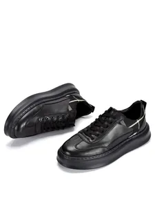 Macro view of men's black leather sneakers featuring chunky sole and plaid accents.