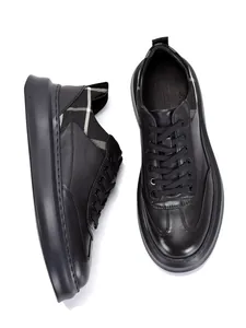 Detailed top and side view of men's black leather sneakers featuring a stylish plaid heel collar
