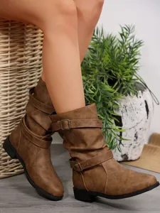 Close-up of brown Western-style slouchy mid-calf boots with buckle straps on model