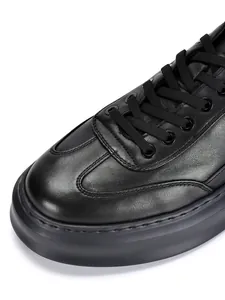 Macro view showing the premium leather texture and stitching of the black casual shoe.