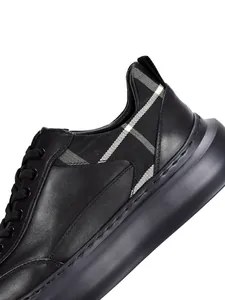 Close-up of premium black leather platform sneaker with classic plaid fabric accent