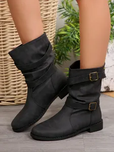 Close-up detail of black western mid-calf boots with decorative buckle straps and round toe