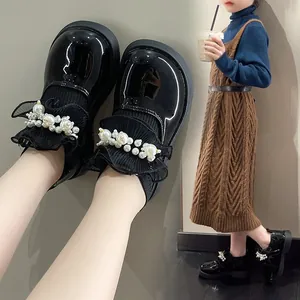 Detailed view of girls' black patent leather shoes with pearls and sock collar.
