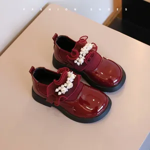 Close-up of burgundy patent leather girls' shoes with pearl and ruffle details