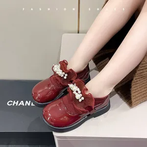 Detail view of burgundy patent leather girls' shoes with pearl and ruffle accents