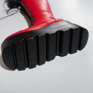 Detailansicht der dicken schwarzen Plateausohle an einem roten Stiefel im Gothic-Stil
