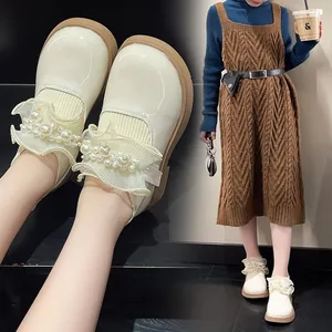 Close-up of girl's cream leather shoes with delicate lace trim and elegant pearl beads