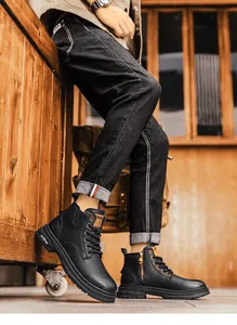 Close-up of men's black leather Martin boots paired with dark denim in a rustic setting